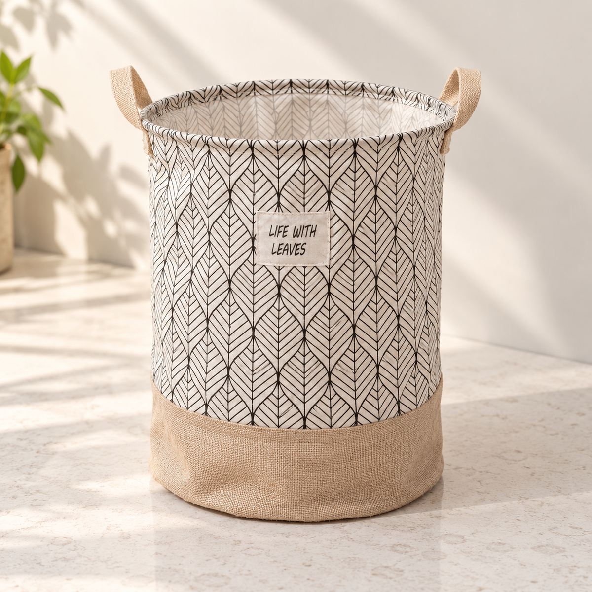Printed fabric laundry basket with handles and leaf pattern in beige and black